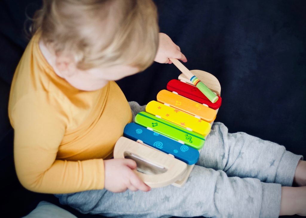 copil mic care se joaca cu un xilofon colorat